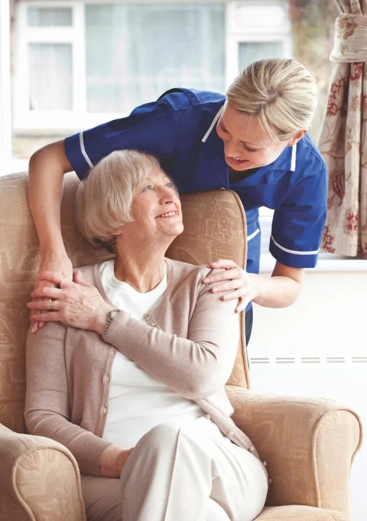 Nurse comforting a smiling older woman in an armchair