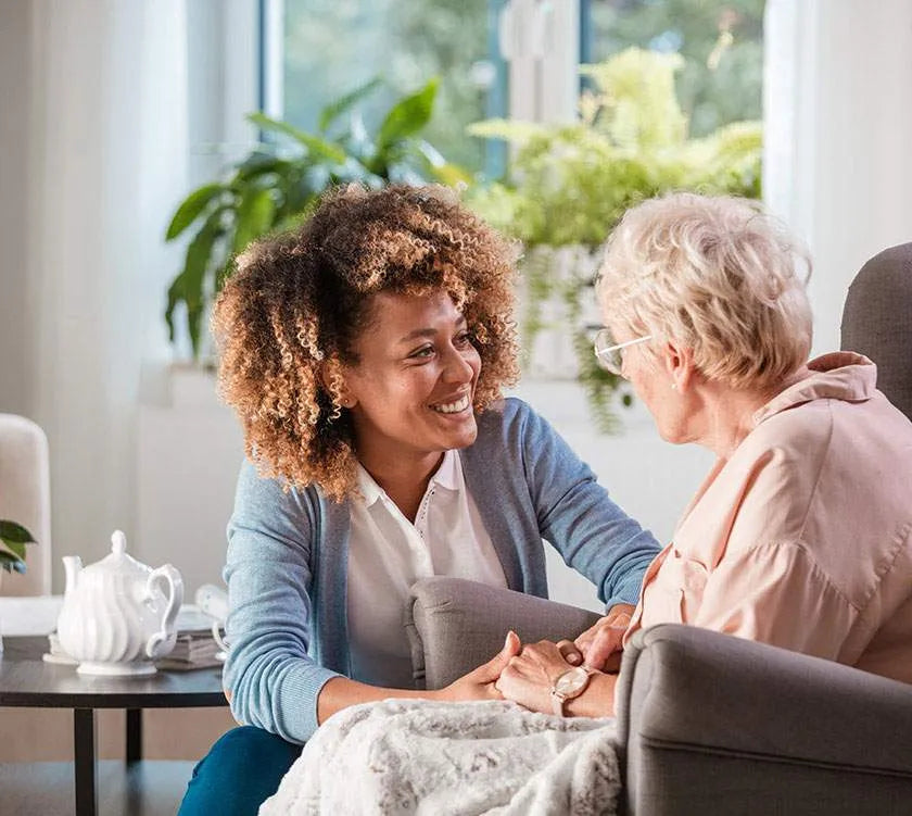 Young woman holding hands with an older woman in a care setting