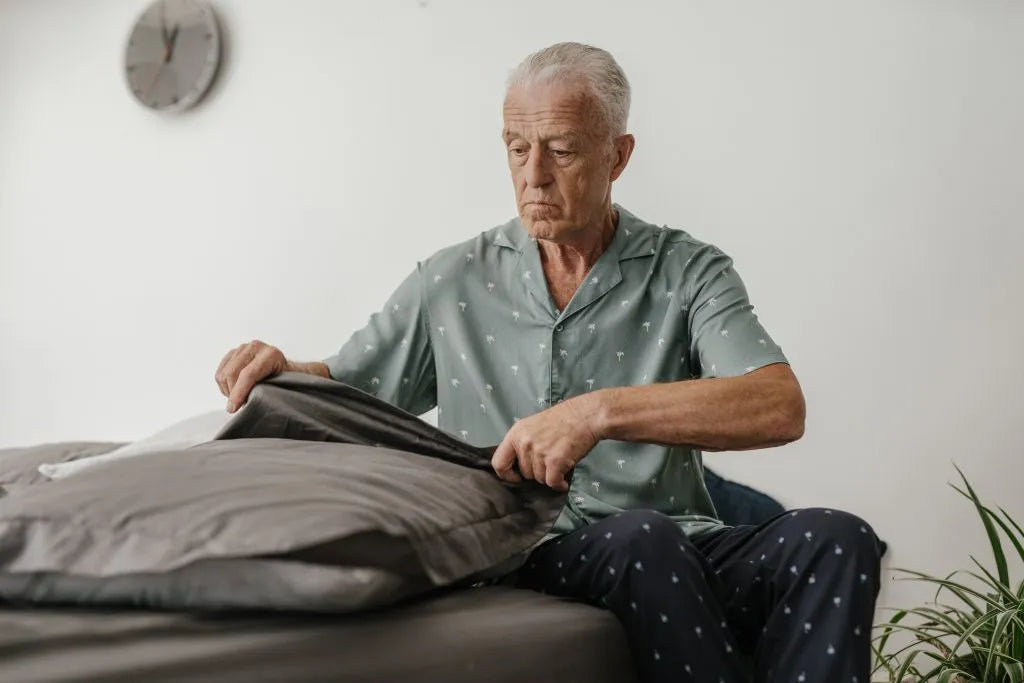 Older man sitting on the side of his bed